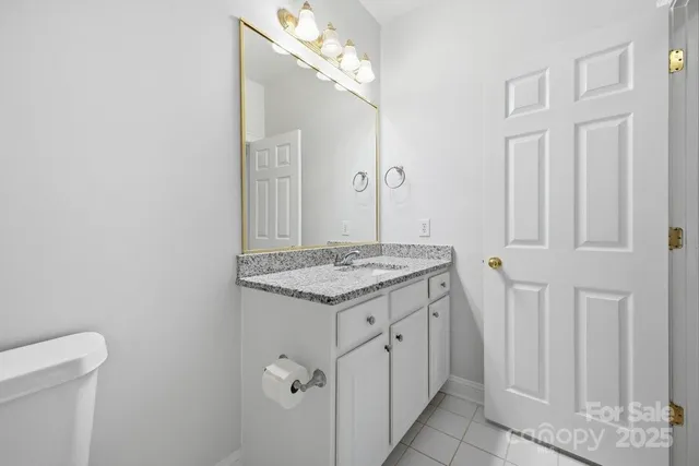 a bathroom with a granite countertop toilet a sink and a mirror