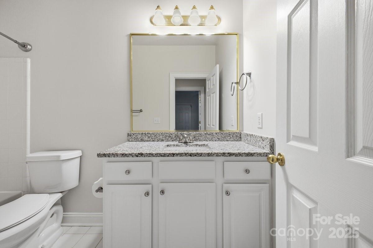 5617 Fairview Road, Unit 6 Charlotte, NC 28209 - Photo 24 of 38 a bathroom with a granite countertop toilet a sink and a mirror