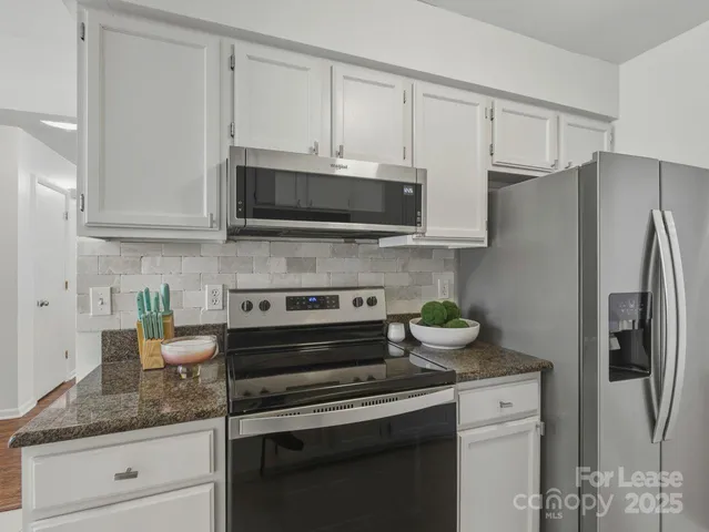 a kitchen with stainless steel appliances granite countertop white cabinets and a stove