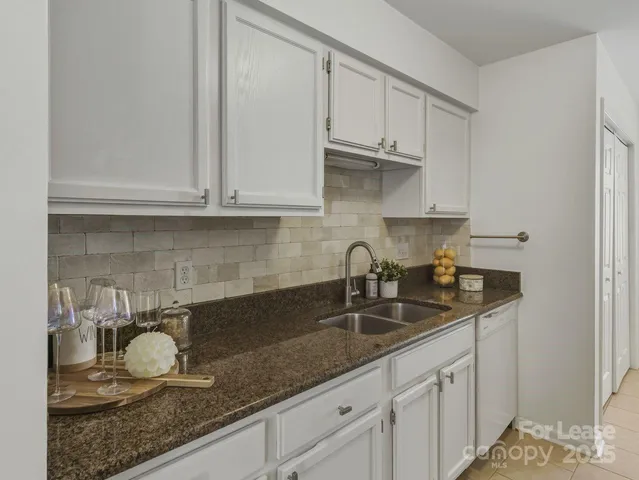 a kitchen with granite countertop a sink a stove and cabinets