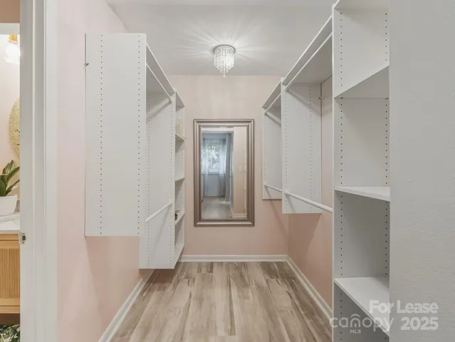 a view of a hallway with wooden floor and a bathroom