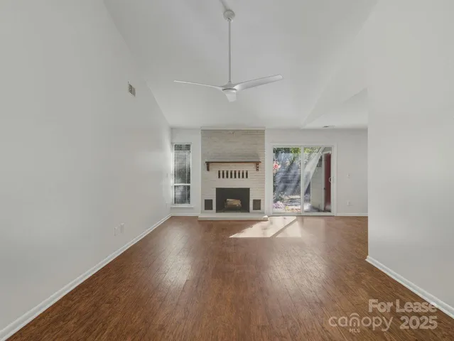 a view of an empty room with a fireplace and a window