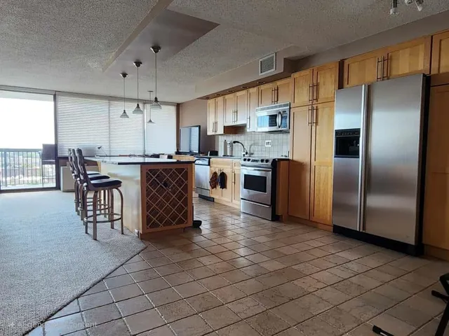 a kitchen with stainless steel appliances a refrigerator a stove a sink a dining table and chairs