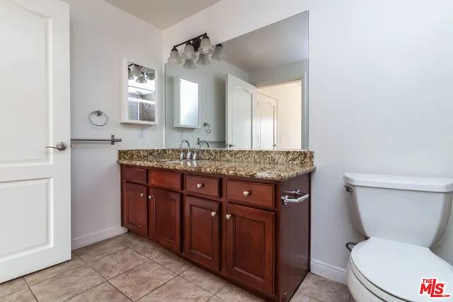 a bathroom with a granite countertop toilet sink and mirror