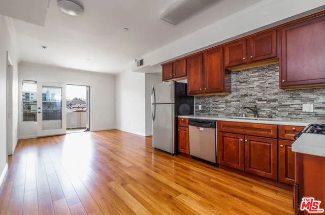 a kitchen with stainless steel appliances granite countertop wooden floors wooden cabinets and sink