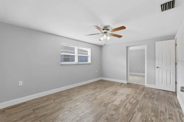 a view of an empty room with wooden floor and a window