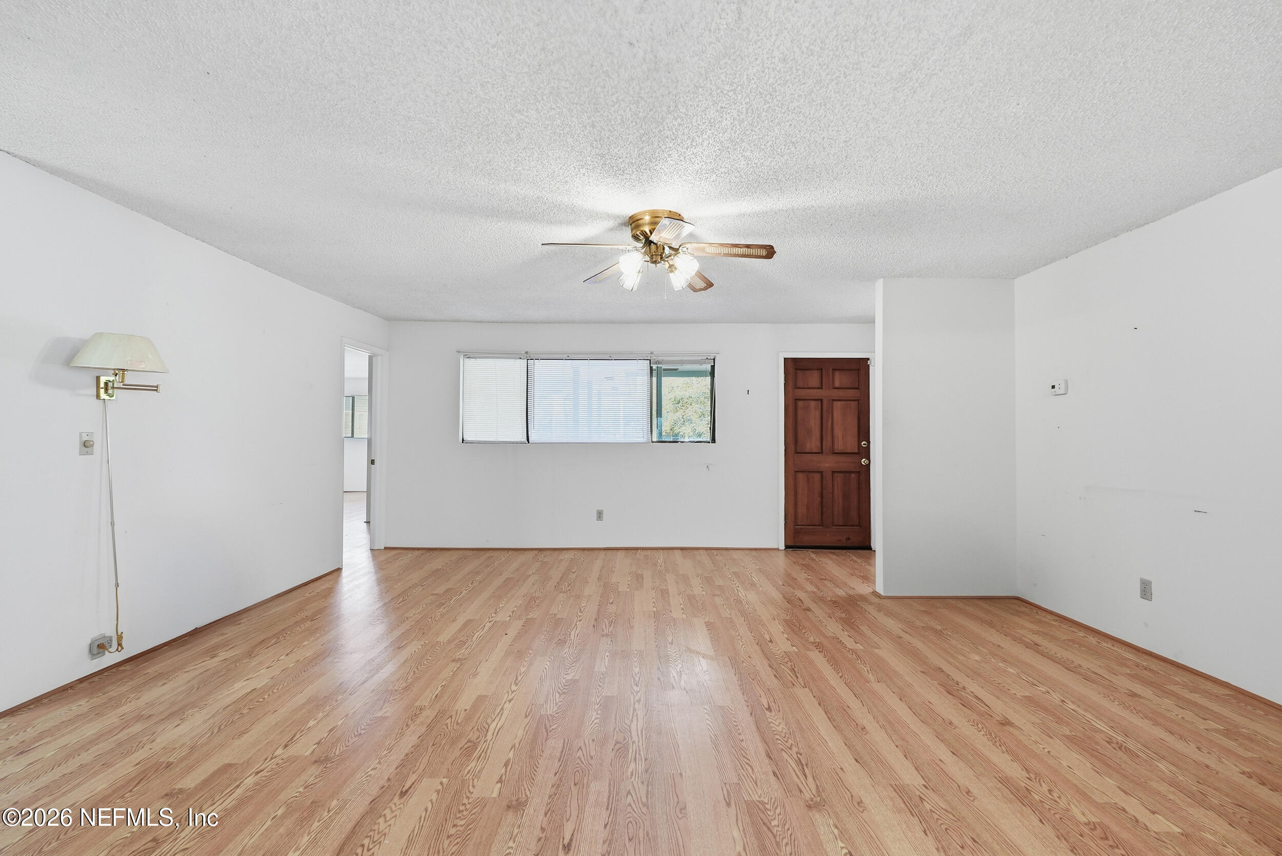 7593 Silver Sands Road Keystone Heights, FL 32656 - Photo 5 of 36 an empty room with wooden floor chandelier fan and windows
