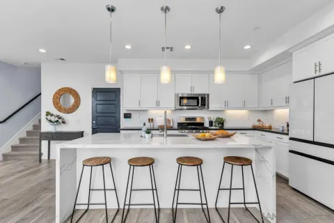 a kitchen with stainless steel appliances granite countertop a sink a stove a refrigerator and white cabinets with wooden floor