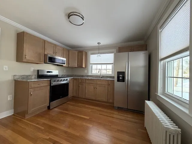 a kitchen with granite countertop a refrigerator cabinets and wooden floor
