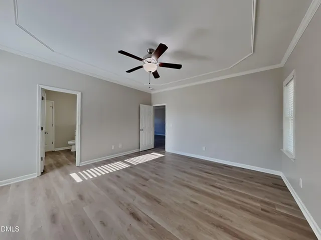 an empty room with wooden floor and ceiling fan