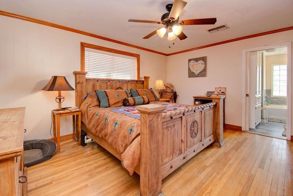 3298 Hawk Road Levelland, TX 79336 - Photo 12 of 32 a spacious bedroom with a bed a ceiling fan and a dresser