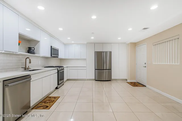 a kitchen with a sink a refrigerator and white cabinets