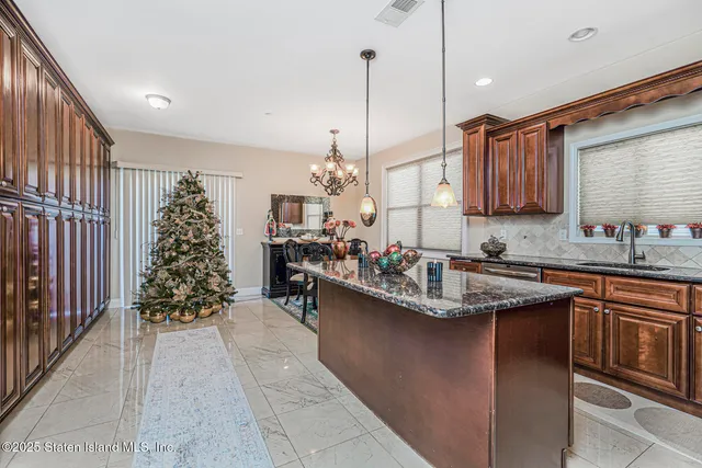 a kitchen with kitchen island granite countertop a sink stove and cabinets
