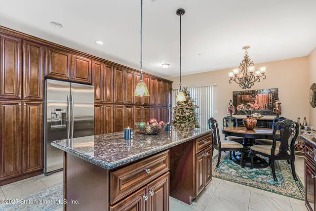 a kitchen with granite countertop kitchen island stainless steel appliances a table chairs sink and wooden floor