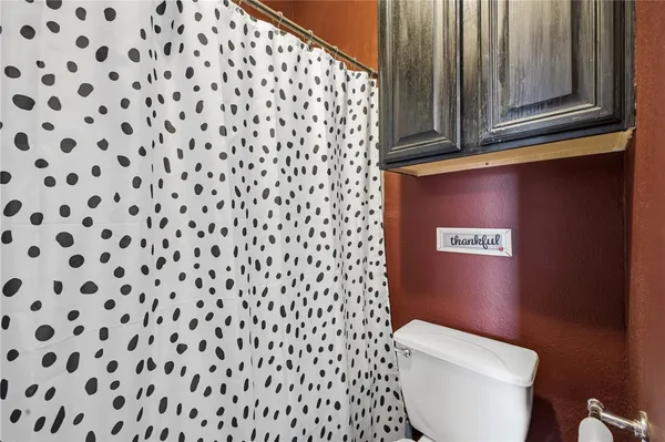 a bathroom with a toilet and a shower curtain