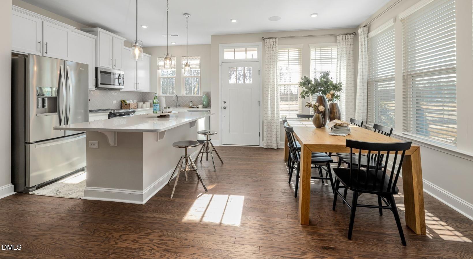 556 Hatters Mill Road, Unit JAMESON Wake Forest, NC 27587 - Photo 8 of 12 a kitchen with stainless steel appliances granite countertop a stove a refrigerator a kitchen island a dining table and chairs with wooden floor