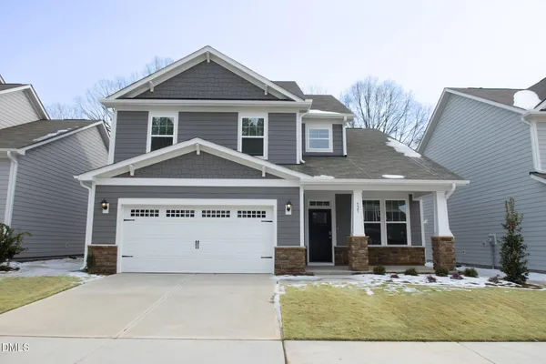 a front view of a house with yard and parking