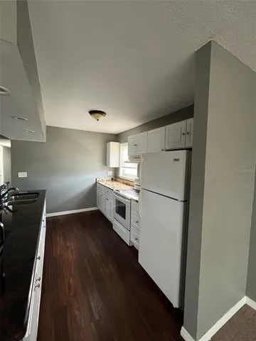 a kitchen with a refrigerator a stove top oven and wooden floor