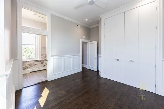 an empty room with wooden floor cabinet and windows