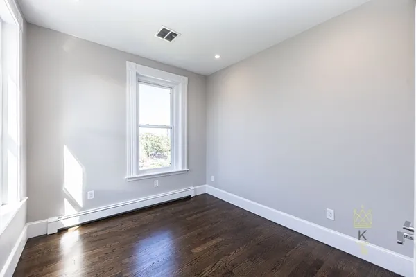 an empty room with wooden floor and window