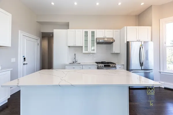 a kitchen with stainless steel appliances a sink a stove a refrigerator and cabinets