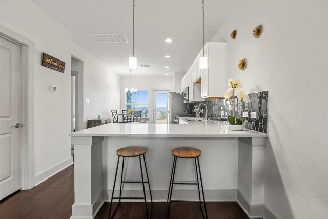 a kitchen with kitchen island a dining table chairs and white cabinets