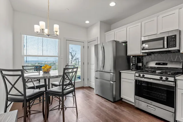 a kitchen with stainless steel appliances a stove a refrigerator a stove a dining table and chairs