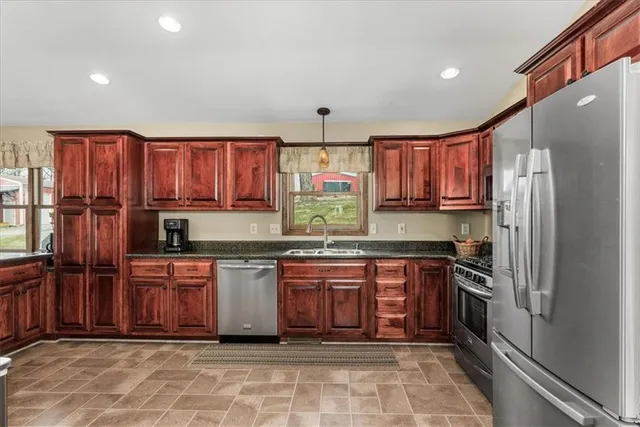 a kitchen with stainless steel appliances granite countertop a stove top oven a refrigerator a sink and dishwasher