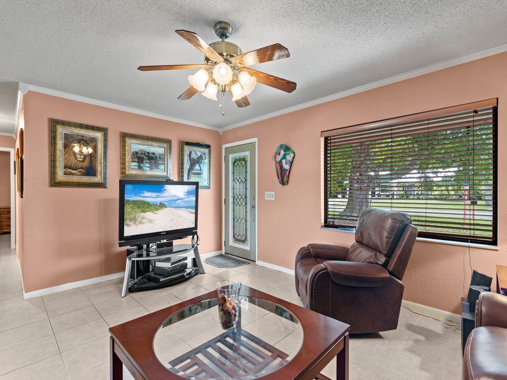 7506 Donlon Road Fort Pierce, FL 34951 - Photo 4 of 23 a living room with furniture a chandelier and a flat screen tv
