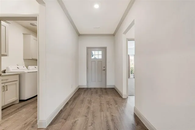 a view of a hallway with wooden floor and a bathroom