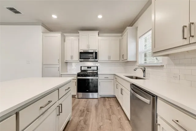 a kitchen with stainless steel appliances a sink dishwasher a stove and a refrigerator