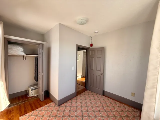 a view of a hallway with wooden floor and a cabinet