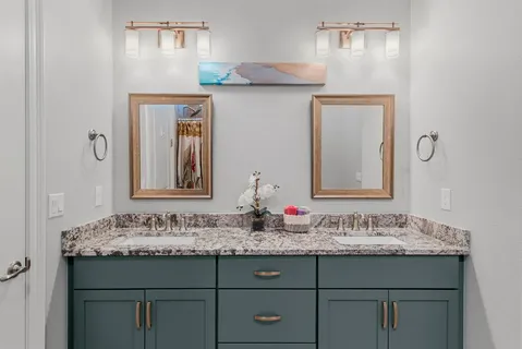a bathroom with a granite countertop sink a mirror and a shower