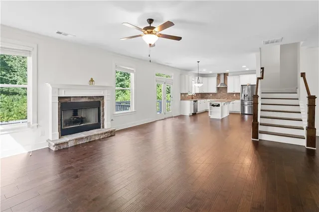 a view of an empty room with wooden floor fireplace and a window