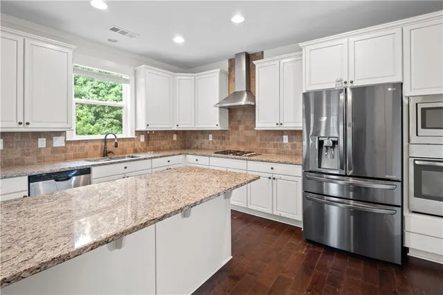 a kitchen with granite countertop stainless steel appliances a refrigerator sink and microwave