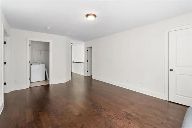 a view of an empty room with wooden floor and closet