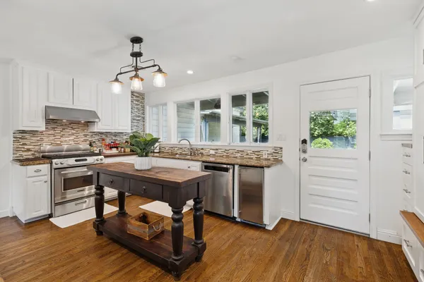 a kitchen with kitchen island a counter top space a sink stainless steel appliances and cabinets