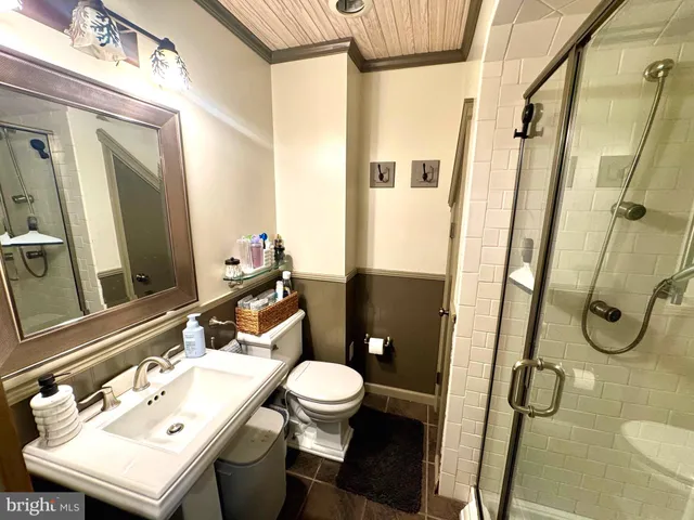 a bathroom with a sink a toilet a mirror and shower
