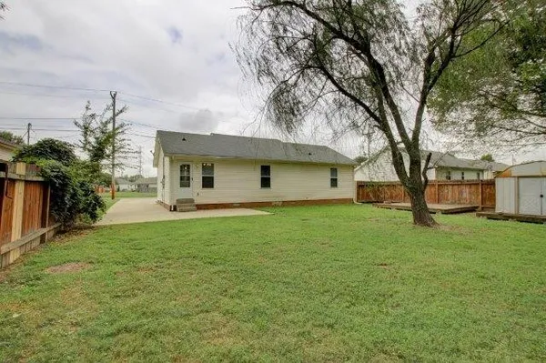 a backyard of a house with plants and large tree