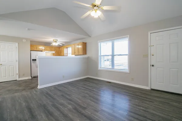 an empty room with wooden floor fan and windows