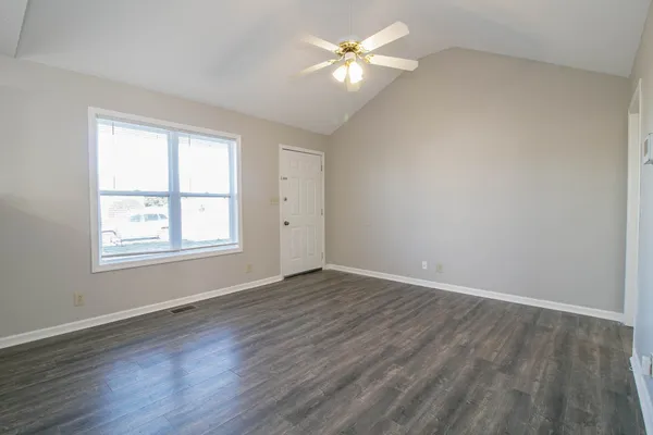a view of an empty room with a window and wooden floor