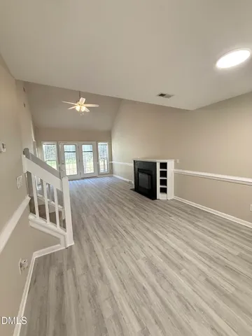 a view of an empty room with wooden floor and a window