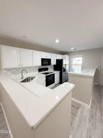 a kitchen with stainless steel appliances a refrigerator a stove a sink and white cabinets