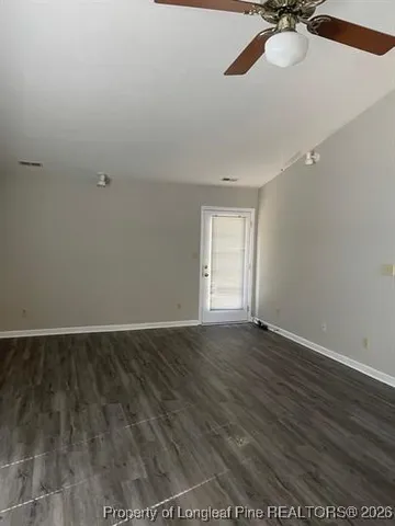 an empty room with wooden floor fan and windows