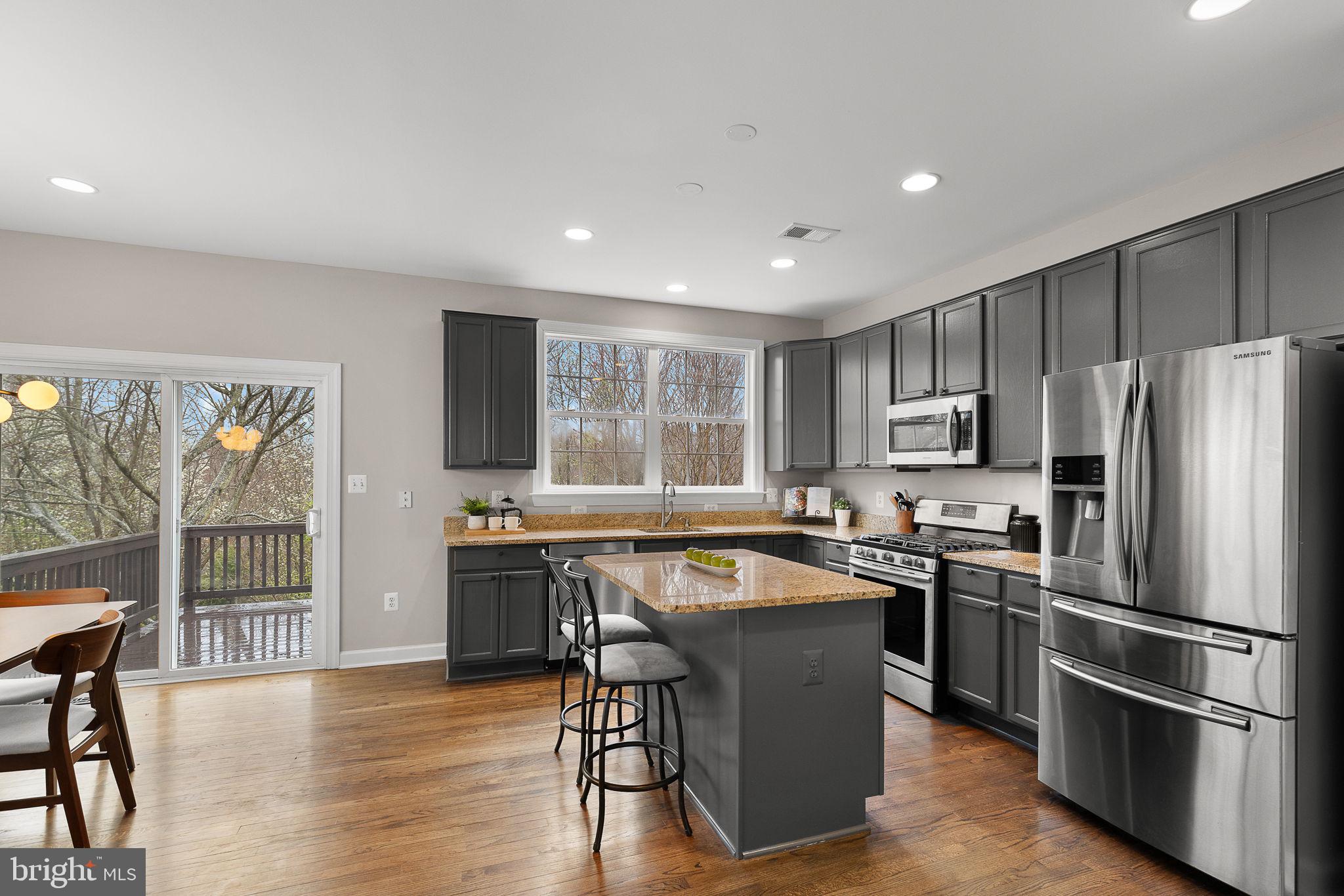 15686 Avocet Loop Woodbridge, VA 22191 - Photo 8 of 33 a kitchen with stainless steel appliances granite countertop a stove a refrigerator a sink a dining table and chairs with wooden floor