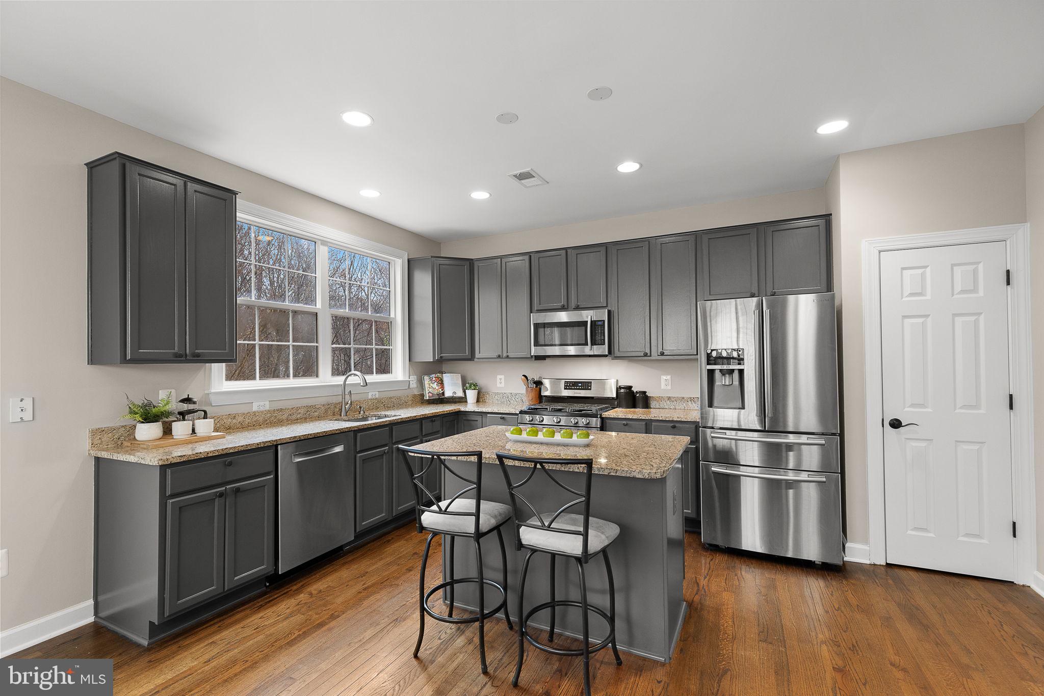 15686 Avocet Loop Woodbridge, VA 22191 - Photo 9 of 33 a kitchen with stainless steel appliances a sink a stove a refrigerator cabinets and wooden floor