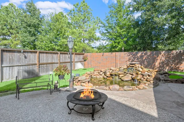 a view of a backyard with table and chairs potted plants and a large tree