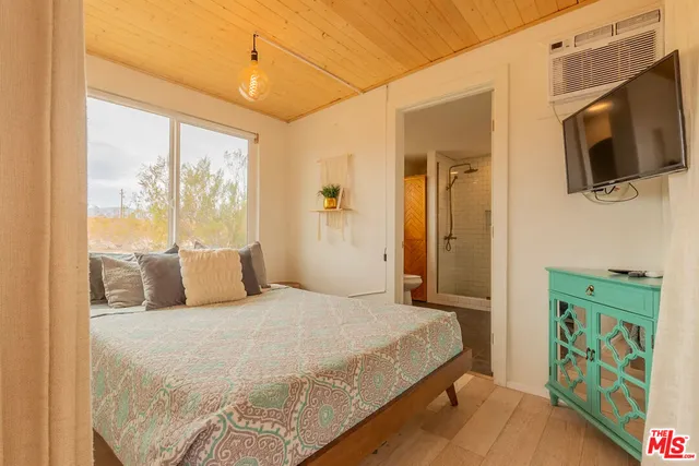 a bedroom with a bed a flat screen tv and a window