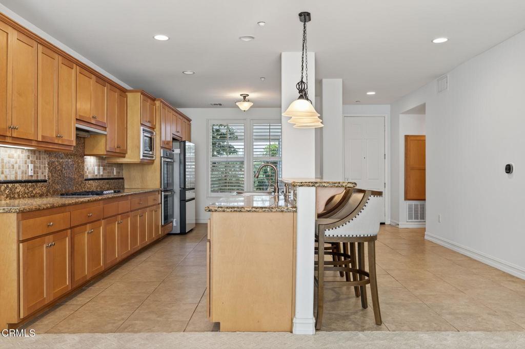 1423 Windshore Way Oxnard, CA 93035 - Photo 22 of 77 a kitchen with stainless steel appliances kitchen island granite countertop a refrigerator a stove a sink a dining table and chairs with wooden floor