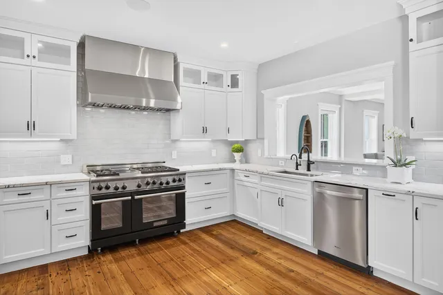 a dining hall with stainless steel appliances granite countertop a dining table chairs and wooden floor